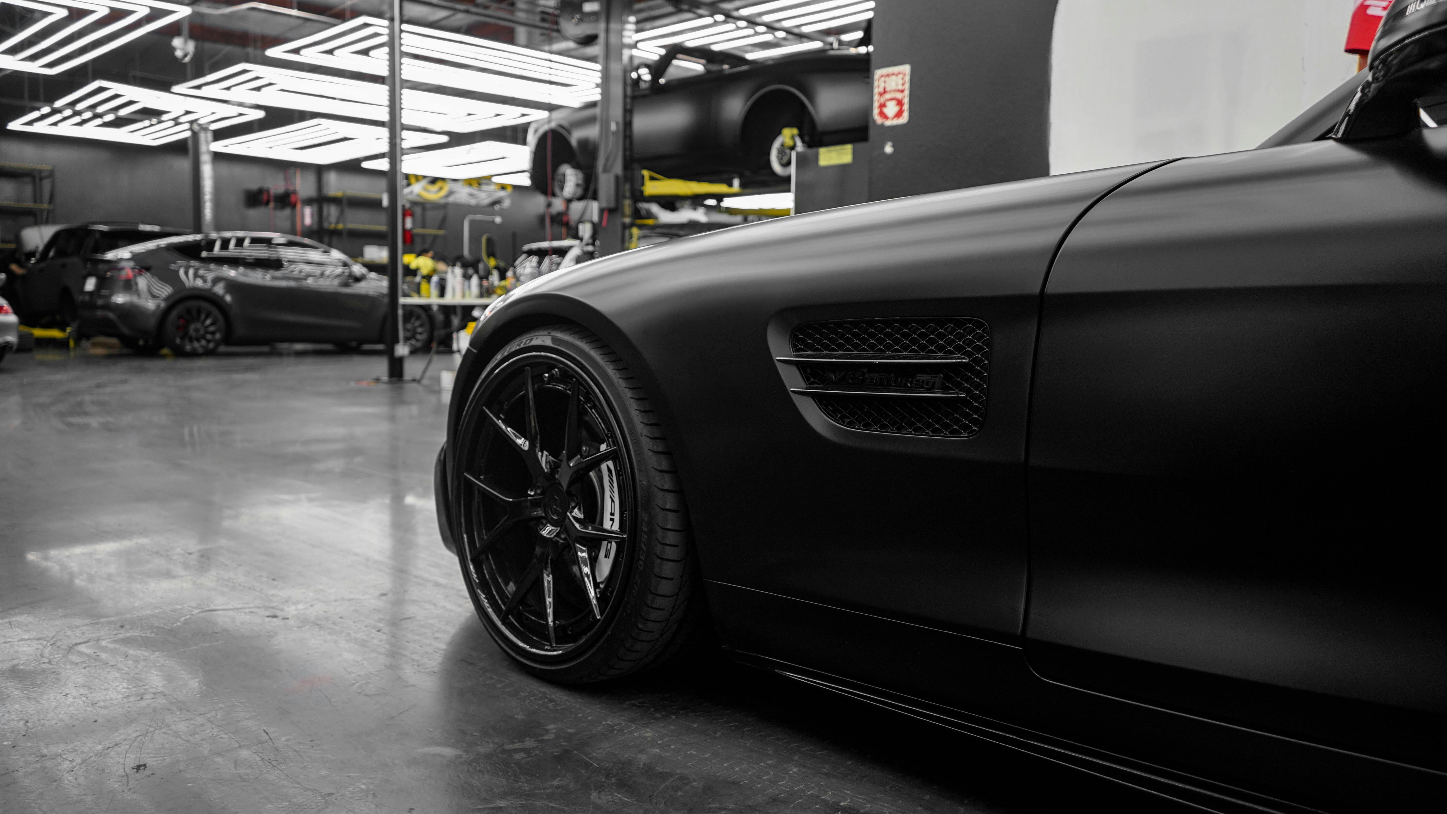 Sleek black sports car in a high-end automotive garage with modern lighting.